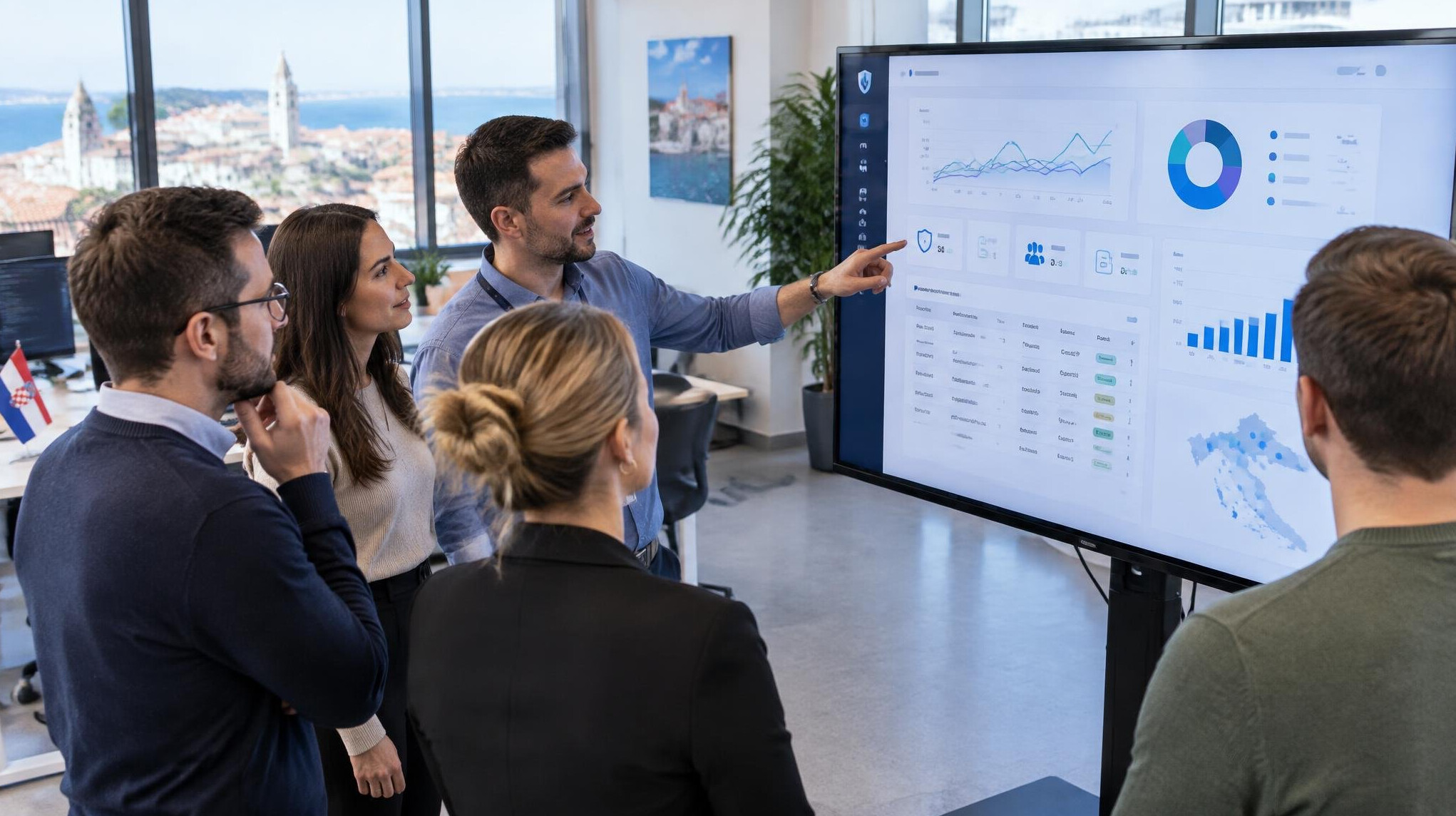 Team of software developers reviewing an insurance dashboard on a large screen in a modern office